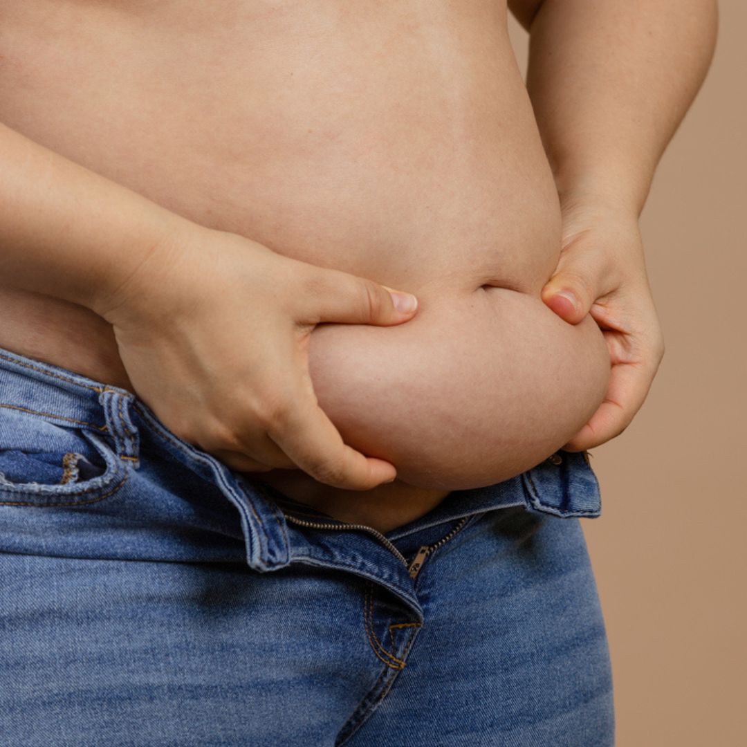woman in jeans holding stomach