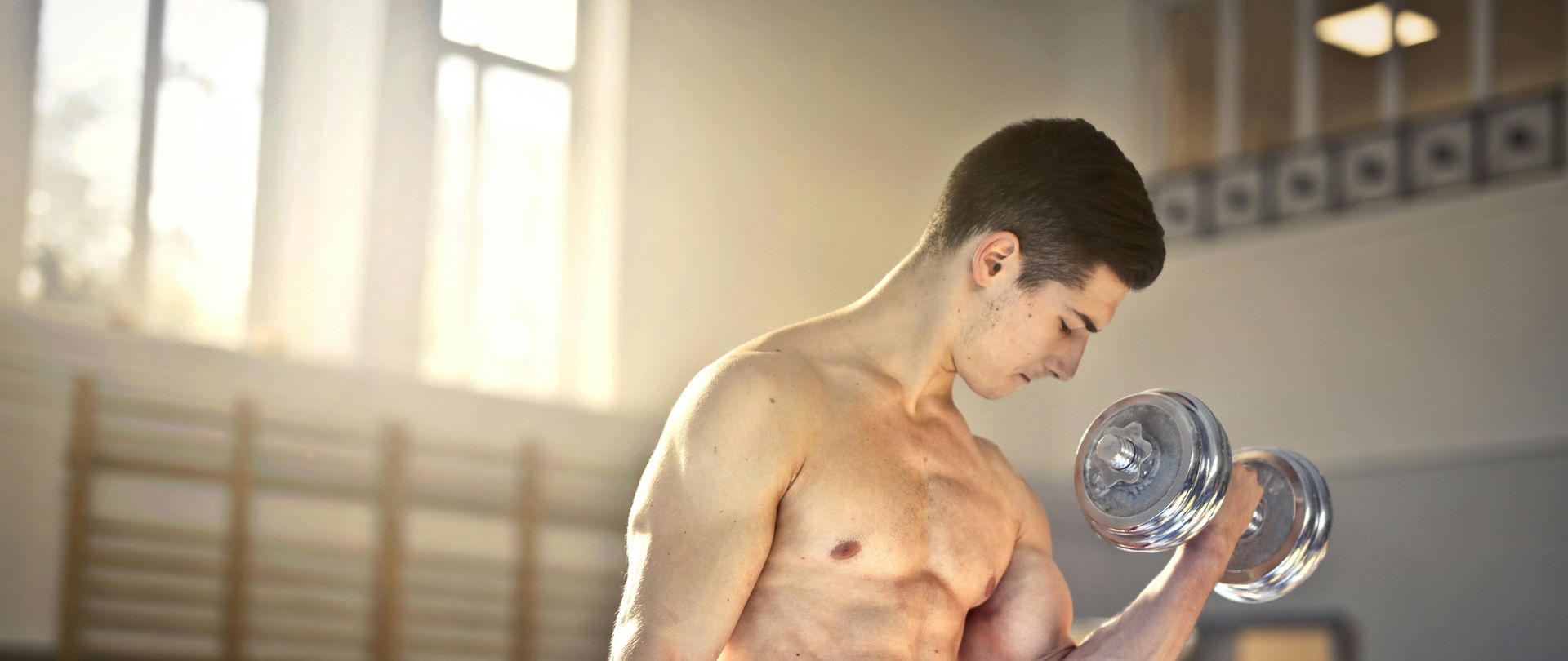 man lifting silver dumbbells